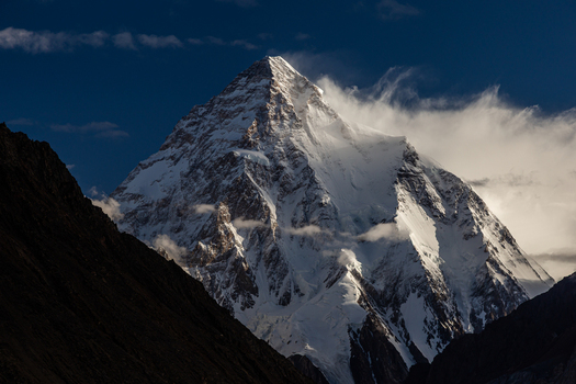 View of the snow capped K2 mountain peak rising against a deep blue sky with wispy clouds and dramatic shadows at Concordia k2 Base Gilgit Baltistan Pakistan. View of the snow capped K2 mountain peak rising against a deep blue sky with wispy clouds and dramatic shadows at Concordia k2 Base Gilgit Baltistan Pakistan.