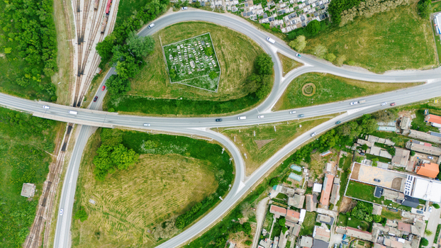 Aerial view of a highway interchange with cars driving through green fields and residential areas in Sabac Vojvodina Serbia.
