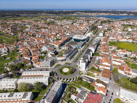 Aerial view of terracotta rooftops and modern architecture converge under a clear sky framed by distant waters and greenery Espinho Portugal. Aerial view of terracotta rooftops and modern architecture converge under a clear sky framed by distant waters and greenery Espinho Portugal.