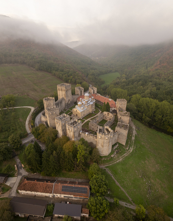Aerial view of Manasija Monastery a medieval Serbian Orthodox monastery with fortified walls and towers nestled in a lush green valley with misty hills in Despotovac Pomoravski okrug Serbia.