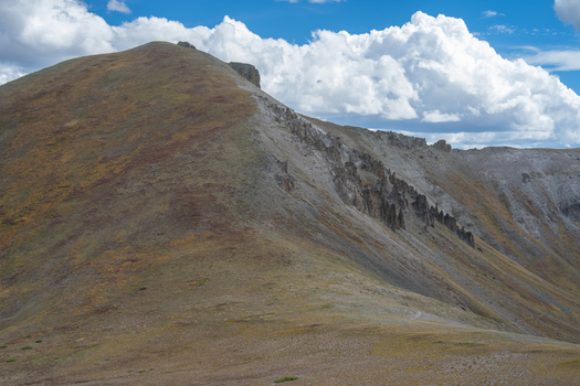 View of San Luis Peak with rugged rocky slopes and a clear blue sky with white clouds in Creede Colorado United States. View of San Luis Peak with rugged rocky slopes and a clear blue sky with white clouds in Creede Colorado United States.