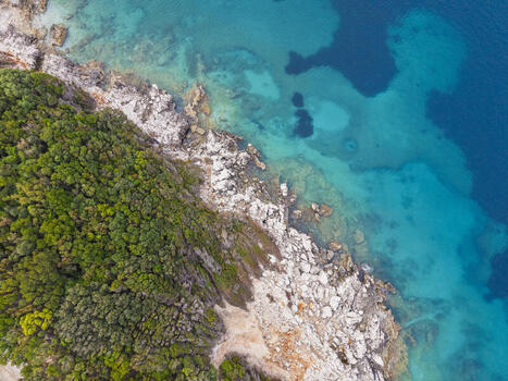 Aerial view of the rocky coastline with lush green vegetation meeting the turquoise Ionian Sea in Ksamil Vlore County Albania. Aerial view of the rocky coastline with lush green vegetation meeting the turquoise Ionian Sea in Ksamil Vlore County Albania.