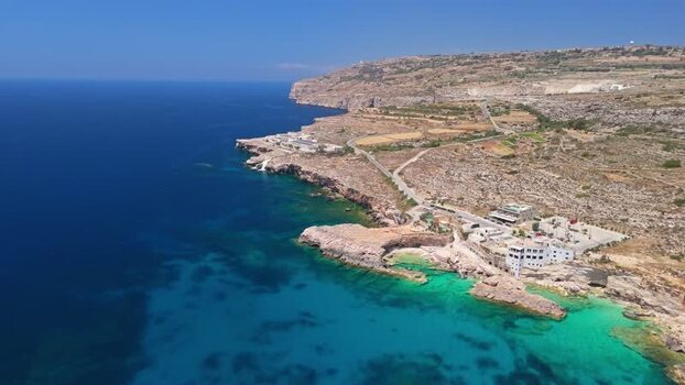 Aerial view of Ghar Lapsi cove in Malta with turquoise sea and cliffs below Aerial view of Ghar Lapsi cove in Malta with turquoise sea and cliffs below