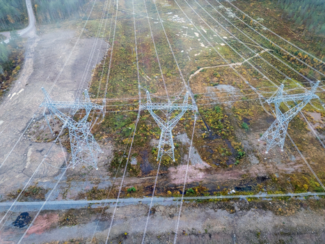 Aerial view of high power electricity infrastructure with steel pylons and power lines stretching across a forest clearing in Muhos North Ostrobothnia Finland.