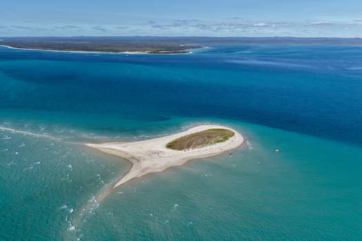 Aerial view of Pelican Bank a small sand island with sparse vegetation surrounded by turquoise and deep blue ocean waters off the coast of K gari Queensland Australia. Aerial view of Pelican Bank a small sand island with sparse vegetation surrounded by turquoise and deep blue ocean waters off the coast of K gari Queensland Australia.