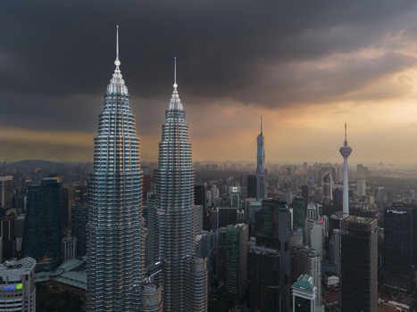 Kuala Lumpur Malaysia 11 March 2026 Aerial view of the Petronas Twin Towers and the city skyline under a dramatic sunset sky with dark storm clouds.