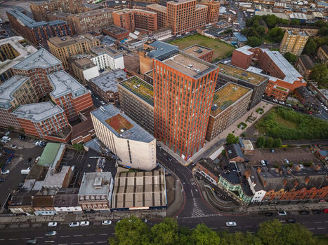 Aerial view of modern and historic buildings including a prominent red brick tower surrounded by urban rooftops and streets in Birmingham England United Kingdom.