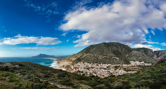 View of the coastal village nestled at the foot of green mountains along the Mediterranean coastline Buggerru Sardinia Italy. View of the coastal village nestled at the foot of green mountains along the Mediterranean coastline Buggerru Sardinia Italy.