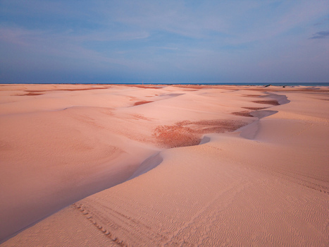 Aerial view of the sand dunes stretch out under a vast sky the landscape painted in hues of sun kissed peach and soft blue Hamlah Socotra Yemen.