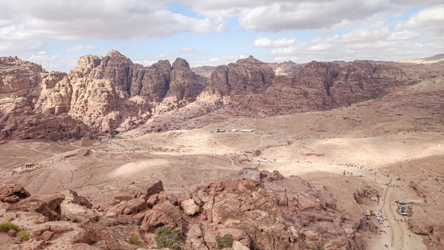 View of the rugged desert landscape and rocky mountains surrounding the historic site of Wadi Musa featuring arid terrain and clear blue skies in Wadi Musa Ma an Governorate Jordan. View of the rugged desert landscape and rocky mountains surrounding the historic site of Wadi Musa featuring arid terrain and clear blue skies in Wadi Musa Ma an Governorate Jordan.
