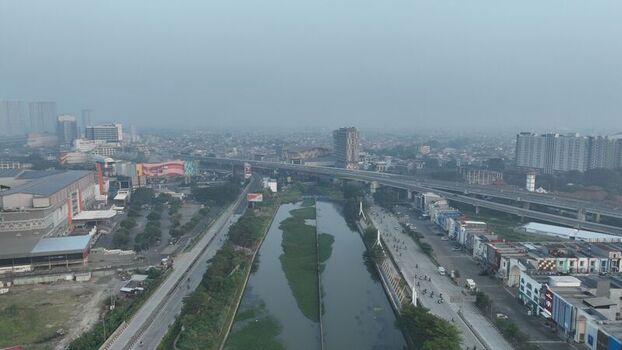 Bekasi Barat West Java Indonesia 20 June 2026 Aerial view of the urban landscape with a canal elevated highway and surrounding buildings under a hazy sky. Bekasi Barat West Java Indonesia 20 June 2026 Aerial view of the urban landscape with a canal elevated highway and surrounding buildings under a hazy sky.