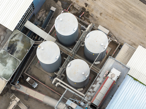 Aerial view of four large industrial storage tanks with connecting pipes and metal walkways at a manufacturing facility in San Giovanni Valdarno Tuscany Italy.