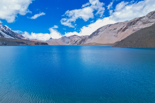 Aerial view of the turquoise waters of Tilicho Lake surrounded by the rugged snow dusted peaks of the Himalayas in Nepal.