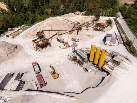 Aerial view of a gravel and sand quarry facility featuring industrial silos conveyor belts heavy machinery and trucks in the countryside of Ortezzano Marche Italy. Aerial view of a gravel and sand quarry facility featuring industrial silos conveyor belts heavy machinery and trucks in the countryside of Ortezzano Marche Italy.