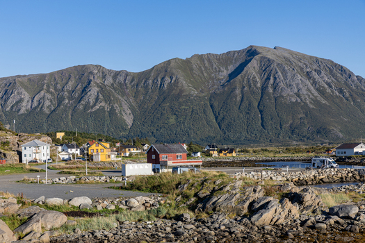 View of the coastal village of Laukvik featuring colorful houses and rocky shores set against a backdrop of majestic mountains in Laukvik Nordland Norway. View of the coastal village of Laukvik featuring colorful houses and rocky shores set against a backdrop of majestic mountains in Laukvik Nordland Norway.