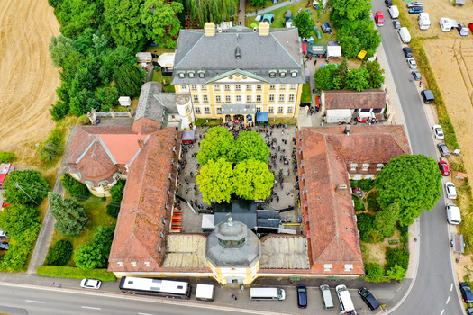 Eggolsheim Germany 09 May 2026 Aerial view of Schloss Jagersburg featuring its historic courtyard filled with people red tiled roofs and lush green trees. Eggolsheim Germany 09 May 2026 Aerial view of Schloss Jagersburg featuring its historic courtyard filled with people red tiled roofs and lush green trees.