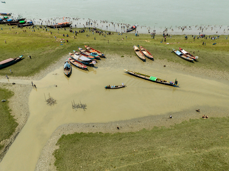 Aerial view of boats resting on the grassy bank near a river as people gather on the shore Charmonai Barisal Division Bangladesh. Aerial view of boats resting on the grassy bank near a river as people gather on the shore Charmonai Barisal Division Bangladesh.