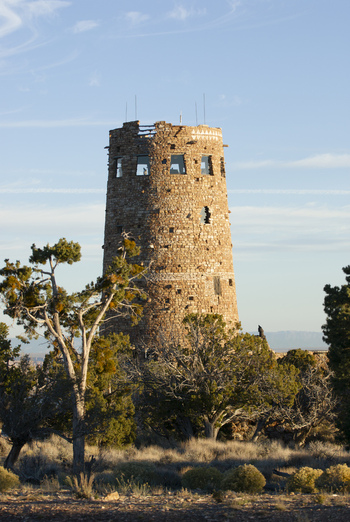 View of the historic Desert View Watchtower surrounded by desert trees and shrubs under a clear blue sky at the Grand Canyon in Coconino County Arizona United States. View of the historic Desert View Watchtower surrounded by desert trees and shrubs under a clear blue sky at the Grand Canyon in Coconino County Arizona United States.