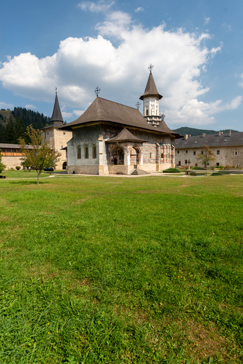 View of the historic Sucevita Monastery with its painted exterior walls and tall towers set in a lush green courtyard under a blue sky in Sucevita Judetul Suceava Romania. View of the historic Sucevita Monastery with its painted exterior walls and tall towers set in a lush green courtyard under a blue sky in Sucevita Judetul Suceava Romania.