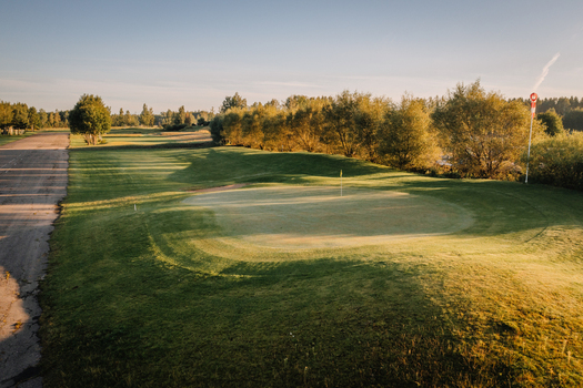 Aerial view of a golf course with green fairways sand bunkers and long tree shadows during golden hour in Valmiera Valmiera Latvija.