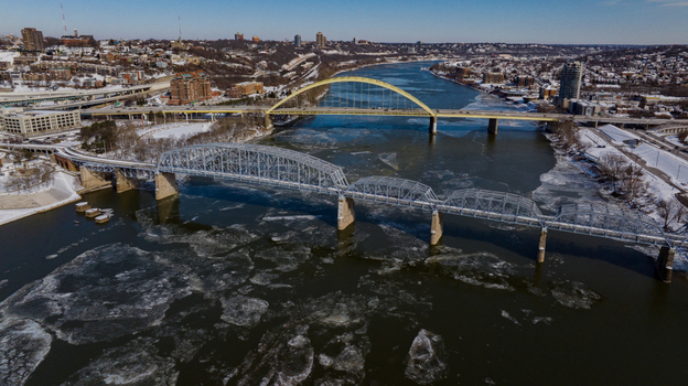 Aerial view of the Ohio River with floating ice floes and historic bridges under a clear winter sky in Cincinnati Ohio United States. Aerial view of the Ohio River with floating ice floes and historic bridges under a clear winter sky in Cincinnati Ohio United States.