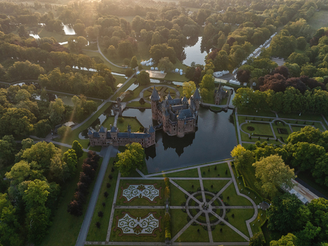 Aerial view of De Haar Castle surrounded by a moat and manicured formal gardens amidst lush green forests during golden hour Utrecht Utrecht Netherlands. Aerial view of De Haar Castle surrounded by a moat and manicured formal gardens amidst lush green forests during golden hour Utrecht Utrecht Netherlands.