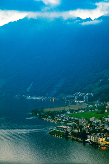 Aerial view of the Swiss Alps overlooking the waterfront buildings lush green fields and mountain slopes in Airolo Ticino Switzerland. Aerial view of the Swiss Alps overlooking the waterfront buildings lush green fields and mountain slopes in Airolo Ticino Switzerland.