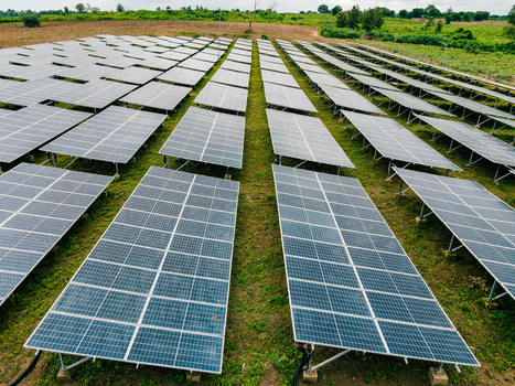 Aerial view of a large solar farm with rows of photovoltaic panels installed on a grassy field in Ogun State Nigeria.