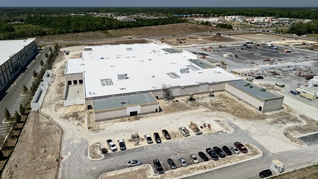 Aerial view of the construction site of a large commercial warehouse on Foundry Lane with white roofing and a busy parking lot in World Golf Village Florida United States.