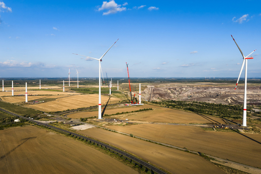 Aerial view of wind turbines under construction with a crane near the Schleenhain lignite open cast mine surrounded by fields under a clear blue sky in Zwenkau Saxony Germany.