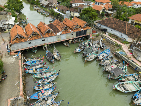 Aerial view of fishing boats clustered at the Jepara Floating Fish Market a vibrant scene where rustic vessels meet the earthy tones of tiled roofs Jepara Central Java Indonesia.