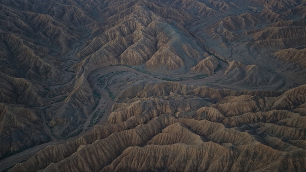 Aerial view of the rugged eroded landscape of the Issyk Kul area with deep canyons winding dry riverbeds and dramatic shadows in Issyk Kul Region Kyrgyzstan. Aerial view of the rugged eroded landscape of the Issyk Kul area with deep canyons winding dry riverbeds and dramatic shadows in Issyk Kul Region Kyrgyzstan.