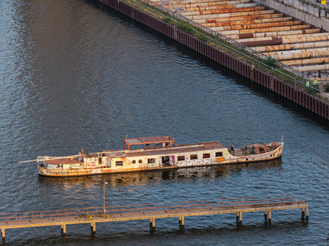 Aerial view of a weathered graffiti covered boat moored in the Spree river near the industrial quay and wooden pier at Berlin Treptower Park in Berlin Berlin Germany. Aerial view of a weathered graffiti covered boat moored in the Spree river near the industrial quay and wooden pier at Berlin Treptower Park in Berlin Berlin Germany.