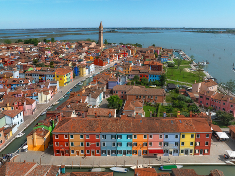 Aerial view of vibrant houses explode in a riot of colors along the canals crowned by the distant San Martino bell tower Burano Veneto Italy. Aerial view of vibrant houses explode in a riot of colors along the canals crowned by the distant San Martino bell tower Burano Veneto Italy.
