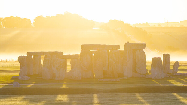 Aerial view of the ancient stone circle of Stonehenge bathed in golden hour light with morning mist over the surrounding grassy fields in Salisbury England United Kingdom. Aerial view of the ancient stone circle of Stonehenge bathed in golden hour light with morning mist over the surrounding grassy fields in Salisbury England United Kingdom.