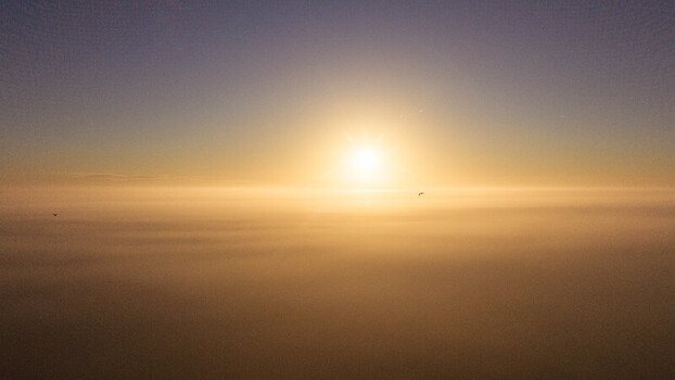 Aerial view of a golden sunrise breaking through a thick layer of clouds above the landscape in Salisbury England United Kingdom. Aerial view of a golden sunrise breaking through a thick layer of clouds above the landscape in Salisbury England United Kingdom.