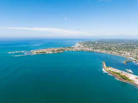 Aerial view of Jungle Beach and the coastal town of Unawatuna with turquoise ocean waters and lush green vegetation under a clear blue sky Unawatuna Sri Lanka. Aerial view of Jungle Beach and the coastal town of Unawatuna with turquoise ocean waters and lush green vegetation under a clear blue sky Unawatuna Sri Lanka.