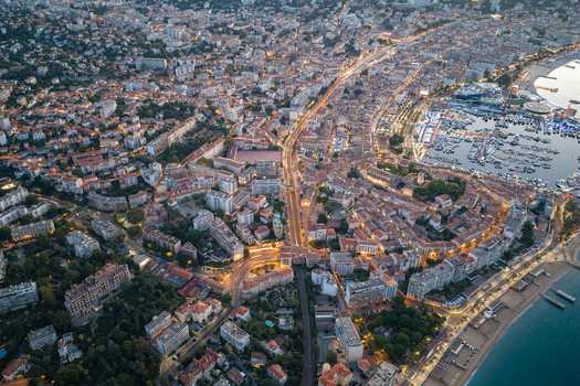 Aerial view of the coastal city of Cannes at twilight featuring the marina illuminated streets and urban architecture along the coast in Cannes Provence Alpes Cote d Azur France. Aerial view of the coastal city of Cannes at twilight featuring the marina illuminated streets and urban architecture along the coast in Cannes Provence Alpes Cote d Azur France.