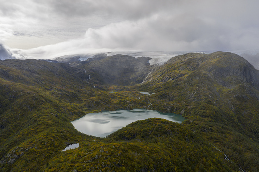 Aerial view of the Buarbreen glacier and turquoise glacial lakes nestled among rugged mountain peaks and autumnal slopes in Ullensvang Vestland Norway. Aerial view of the Buarbreen glacier and turquoise glacial lakes nestled among rugged mountain peaks and autumnal slopes in Ullensvang Vestland Norway.