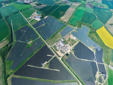 Aerial view of Chelveston Wind Farm with solar panels and wind turbines surrounded by agricultural fields in Wellingborough England United Kingdom. Aerial view of Chelveston Wind Farm with solar panels and wind turbines surrounded by agricultural fields in Wellingborough England United Kingdom.