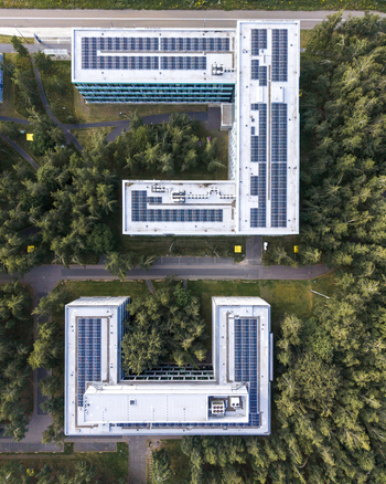 Aerial view of ASML Building 26 at High Tech Campus with solar panels on the rooftops surrounded by lush green forest in Eindhoven Noord Brabant Netherlands. Aerial view of ASML Building 26 at High Tech Campus with solar panels on the rooftops surrounded by lush green forest in Eindhoven Noord Brabant Netherlands.