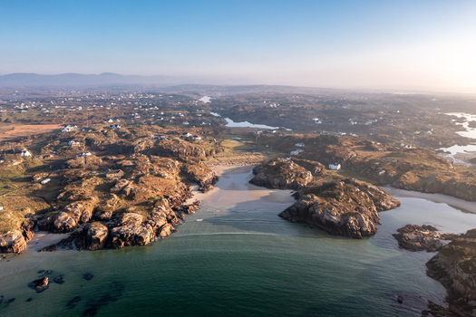 Aerial view of the rugged coastline and sandy beach at Cloughglass featuring rocky outcrops scattered houses and calm coastal waters in Cloughglass County Donegal Ireland. Aerial view of the rugged coastline and sandy beach at Cloughglass featuring rocky outcrops scattered houses and calm coastal waters in Cloughglass County Donegal Ireland.