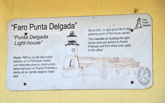 View of an informational sign for the Faro Punta Delgada lighthouse with historical text and a sketch mounted on a yellow wall in Puerto Madryn Chubut Argentina. View of an informational sign for the Faro Punta Delgada lighthouse with historical text and a sketch mounted on a yellow wall in Puerto Madryn Chubut Argentina.