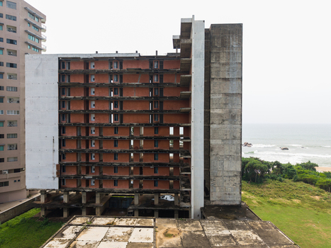 Aerial view of an unfinished concrete building structure with exposed floors near the coastline under an overcast sky in Galle Southern Province Sri Lanka. Aerial view of an unfinished concrete building structure with exposed floors near the coastline under an overcast sky in Galle Southern Province Sri Lanka.