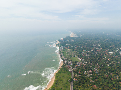 Aerial view of the scenic coastline with sandy beaches lush tropical vegetation and urban settlements along the turquoise ocean in Galle Southern Province Sri Lanka. Aerial view of the scenic coastline with sandy beaches lush tropical vegetation and urban settlements along the turquoise ocean in Galle Southern Province Sri Lanka.