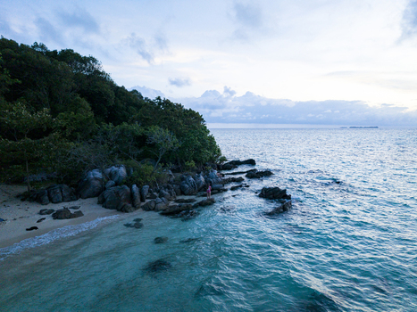 Aerial view of turquoise waters meet the rocky shore and lush greenery of Tanjung Gelam Beach Karimunjawa Central Java Indonesia. Aerial view of turquoise waters meet the rocky shore and lush greenery of Tanjung Gelam Beach Karimunjawa Central Java Indonesia.