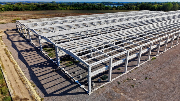 Aerial view of the concrete hall structure under construction featuring a grid of support beams and columns on a gravel site in Kovin Vojvodina Serbia. Aerial view of the concrete hall structure under construction featuring a grid of support beams and columns on a gravel site in Kovin Vojvodina Serbia.