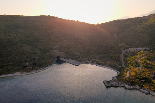 Aerial view of the historic submarine tunnel and coastal hills during golden hour in Porto Palermo Qarku i Vlores Albania. Aerial view of the historic submarine tunnel and coastal hills during golden hour in Porto Palermo Qarku i Vlores Albania.
