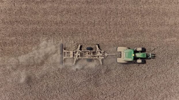 Aerial view of a tractor plowing a dry field in Portugal. Aerial view of a tractor plowing a dry field in Portugal.