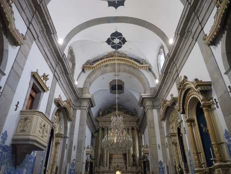 View of the ornate interior of Capela de Santa Catarina church featuring vaulted ceilings golden altars blue and white azulejo tiles and a large crystal chandelier in Porto Portugal. View of the ornate interior of Capela de Santa Catarina church featuring vaulted ceilings golden altars blue and white azulejo tiles and a large crystal chandelier in Porto Portugal.